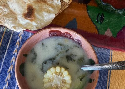 A soup with greens and corn in the bowl
