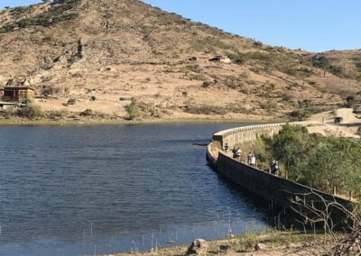 A group of people walking near a lake and mountain
