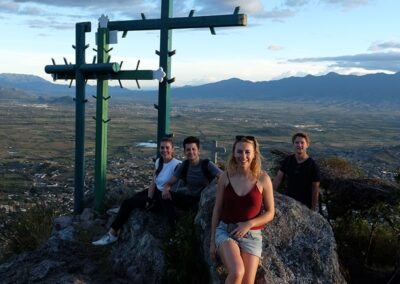 A group of people sitting on top of a big rock on the mountain
