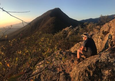 A person sitting on top of a big rock on the mountain
