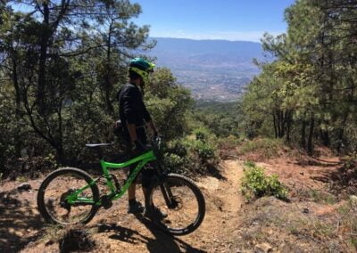 A person standing on mountain while holding the bike