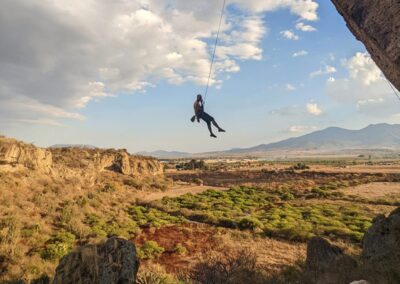 A person doing rock climbing and hanging from a safety rope