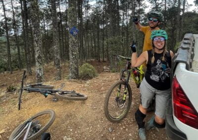 Two people in the forest of mountain near a car and mountain bike