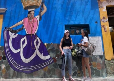 Two women standing in front of a mural wall