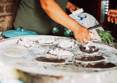 A person giving topping on Memelas, Oaxacan snack