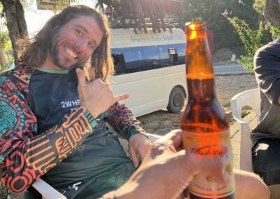 A person sitting near a car with beer