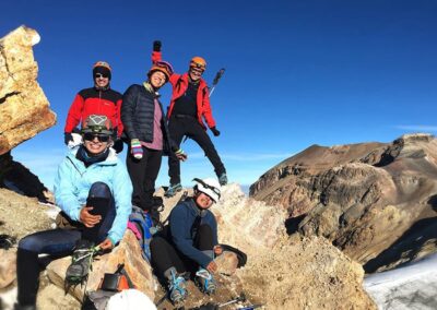 A group of people standing and sitting on top of rocks on the mountain